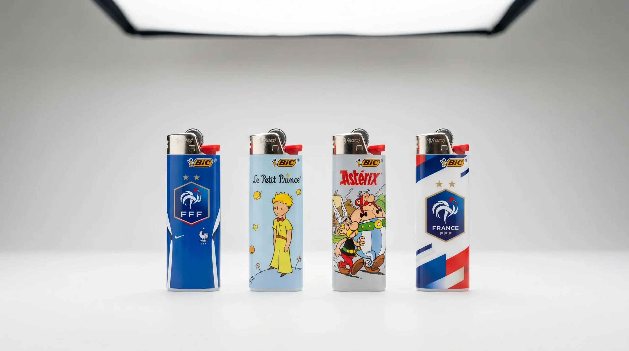 Briquets BIC éditions limitées officielles en ligne horizontale sur fond blanc : collaboration Équipe de France de Football, Le Petit Prince et Astérix, éclairage studio professionnel